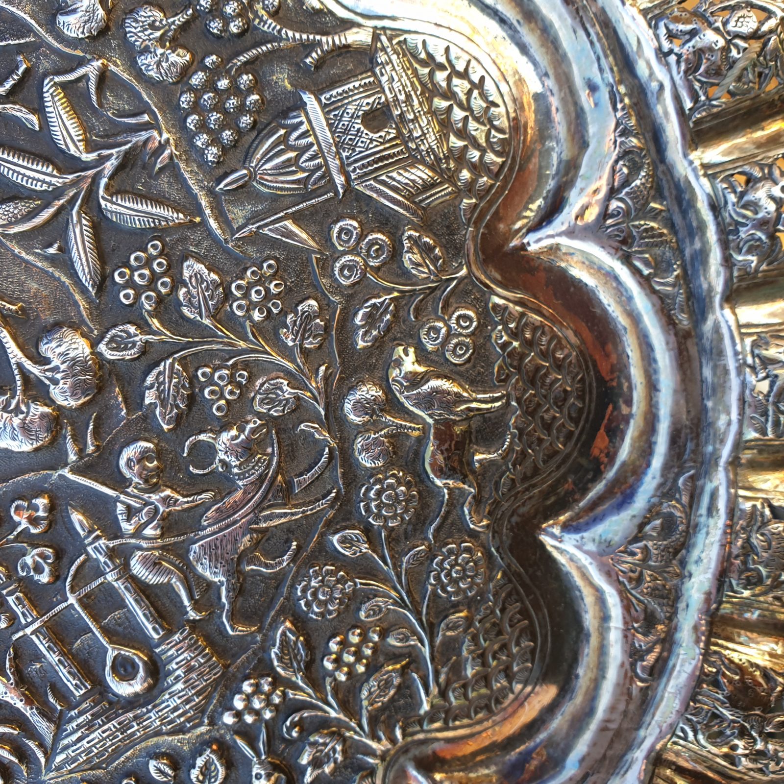 A close-up image of an embossed and  highly decorated Indian antique silver dish.