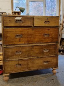 A campaign chest of drawers midway through being restored