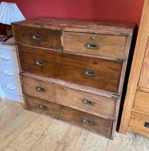 A neglected antique campaign chest of drawers in need of restoration