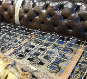 The seat of an antique Chesterfield with its new set of springs securely lashed into place