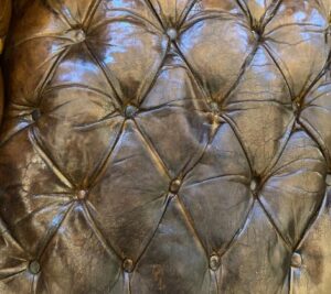 The original, distressed, deep buttoned and pleated seat of the antique Chesterfield