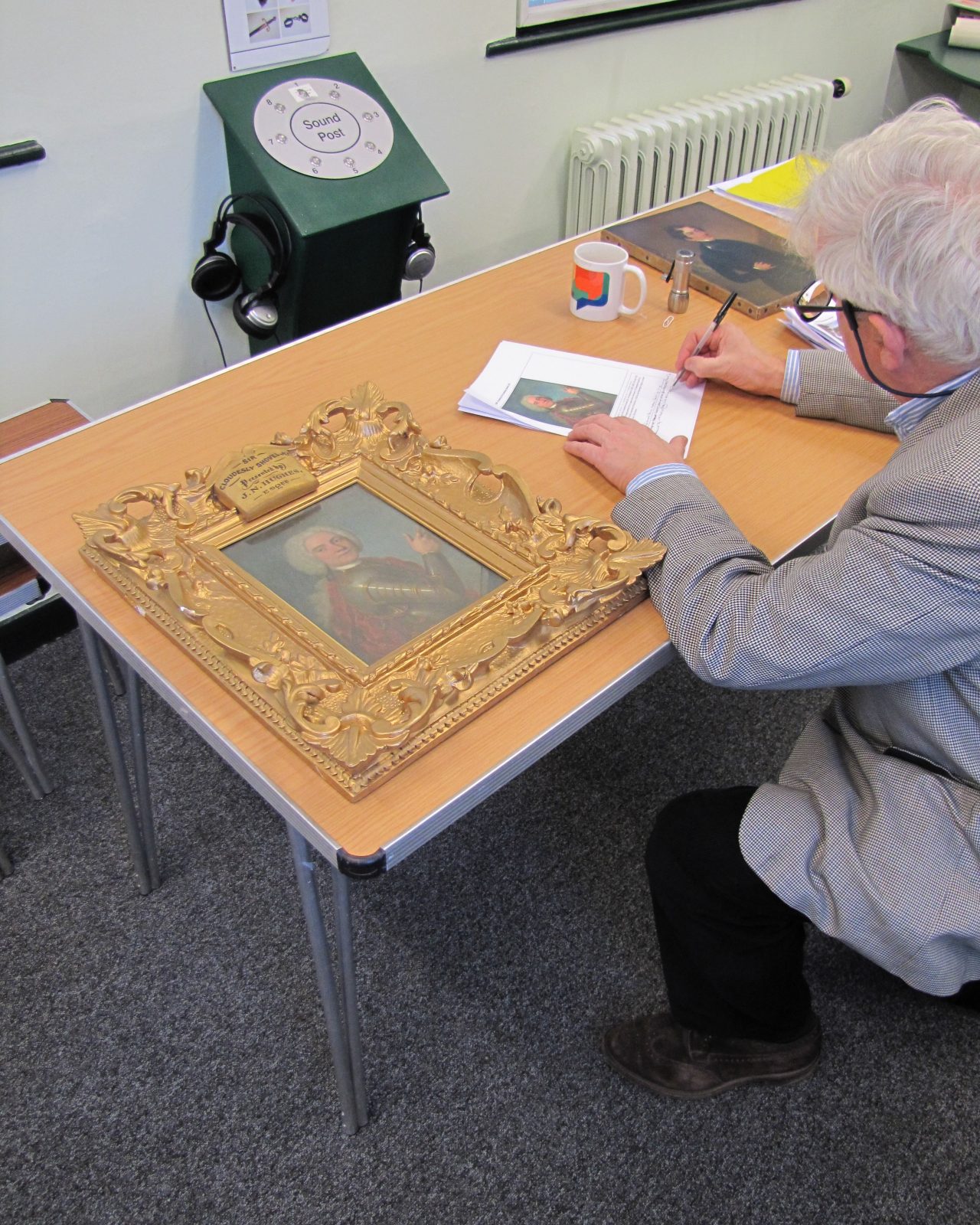 Culvertons' fine art valuer makes notes while examining an oil painting during an art appraisal for insurance purposes.