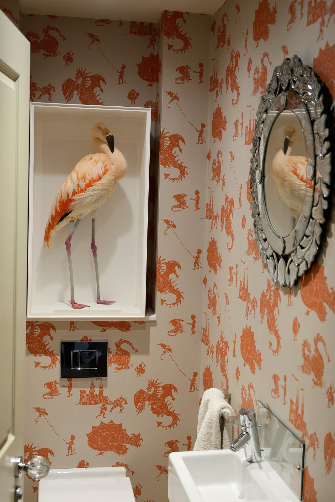 A cased pink flamingo displayed within a bathroom, an example of how antique taxidermy can compliment a modern  interior.