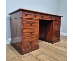 A fine antique mahogany pedestal desk, dating to the 1860s, that benefits from having dummy drawers to the reverse and a newly laid top quality green leather hide writing surface that has been hand-dyed, and its borders enhanced with decorative gold-leaf and blind tooling.