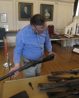 Our antique arms expert closely examines one of the guns from the Guildhall Museum's collection.