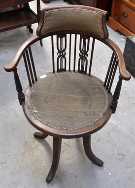 A once elegant, but now neglected piece of Edwardian furniture, this revolving desk chair awaits restoration.   